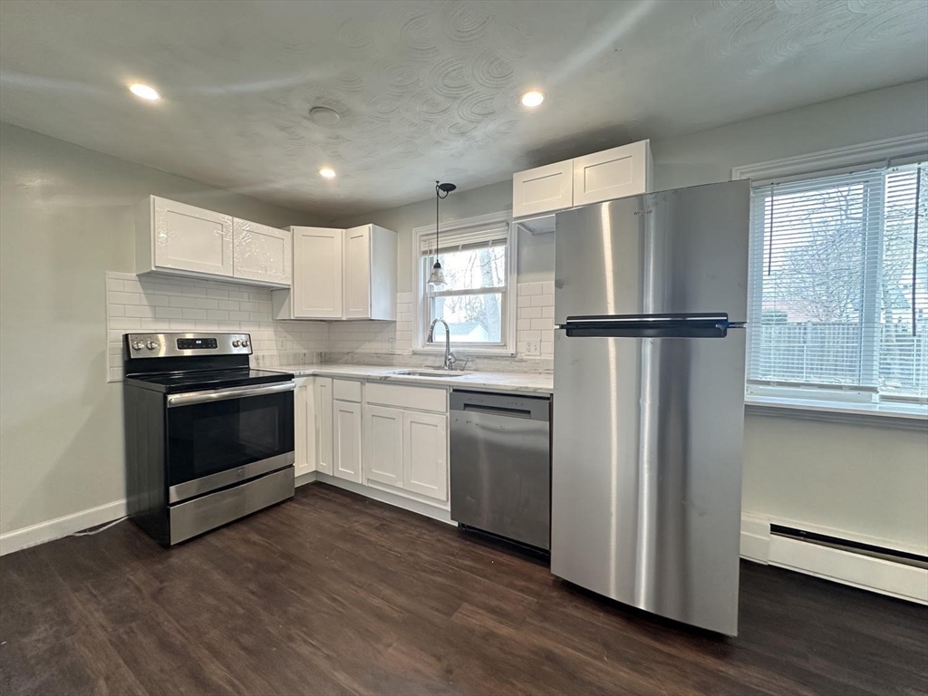 38 Hadley Street Springfield, MA 01118 - Photo 4 of 20 a kitchen with a refrigerator a stove top oven a sink and cabinets