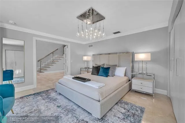 a bedroom with a bed large windows and a chandelier