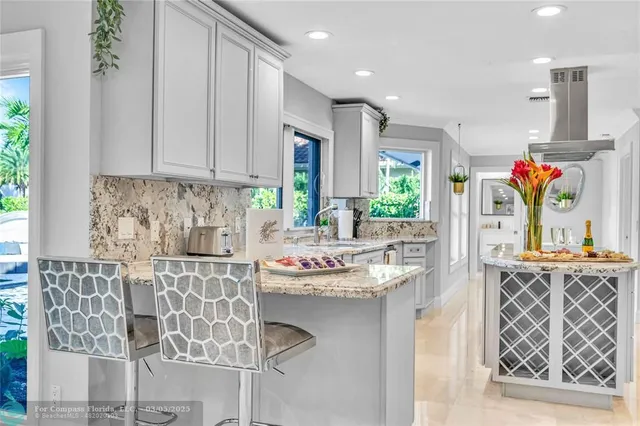 a kitchen with stainless steel appliances kitchen island granite countertop a refrigerator oven a sink dishwasher and white cabinets with wooden floor
