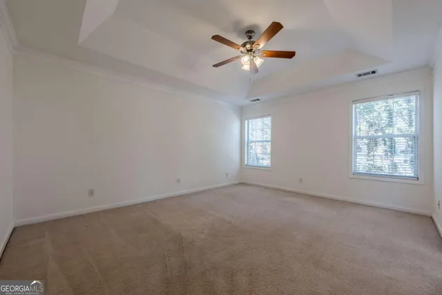 an empty room with windows and fan