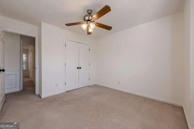 an empty room with closet and a chandelier fan