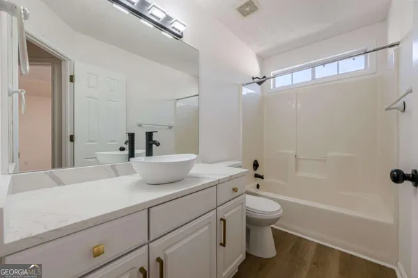 a bathroom with a bathtub shower sink vanity and toilet
