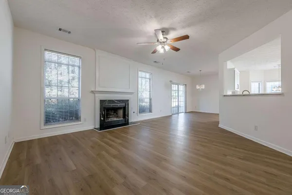 a view of empty room with wooden floor and fan
