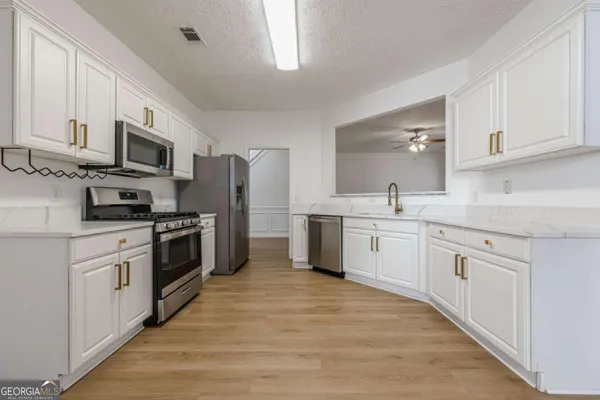 a kitchen with granite countertop white cabinets and stainless steel appliances