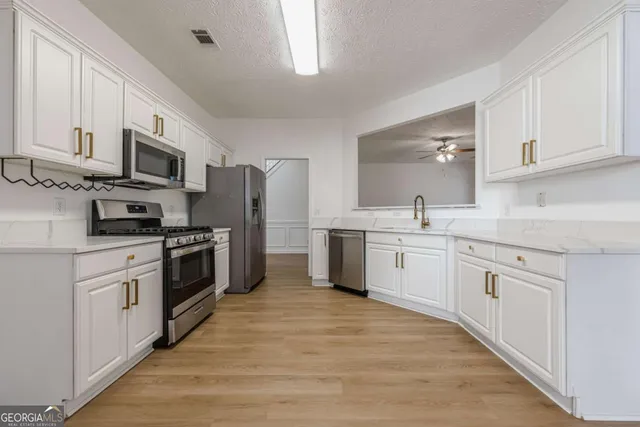 a kitchen with granite countertop white cabinets and stainless steel appliances