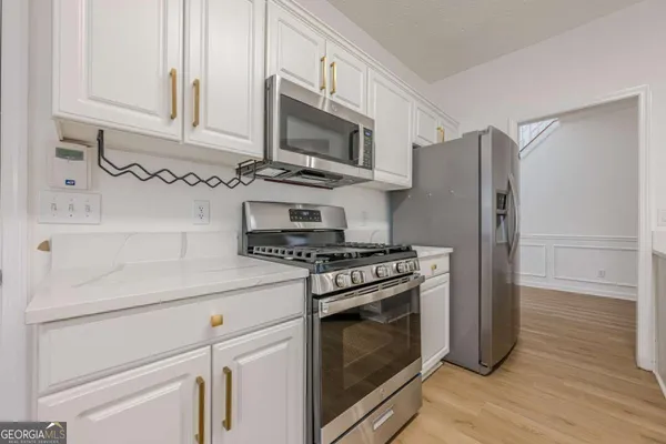 a kitchen with stainless steel appliances white cabinets and a stove a refrigerator with wooden floors