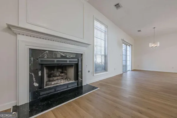 a view of an empty room with wooden floor fireplace and a window