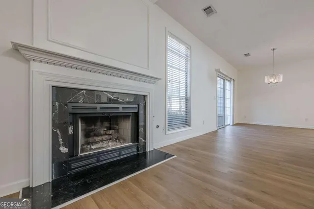 a view of an empty room with wooden floor fireplace and a window