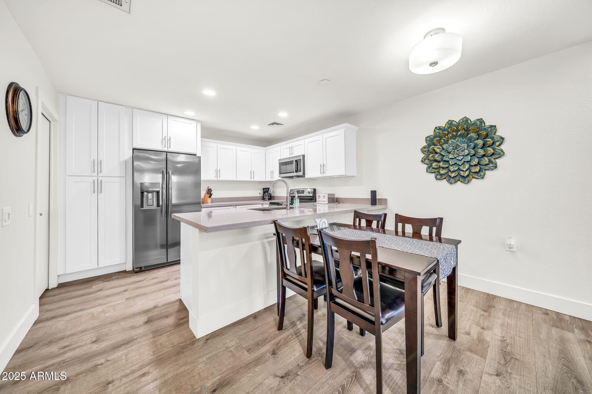 14300 West Bell Road, Unit 423 Surprise, AZ 85374 - Photo 11 of 44 a kitchen with stainless steel appliances granite countertop a dining table chairs refrigerator and microwave