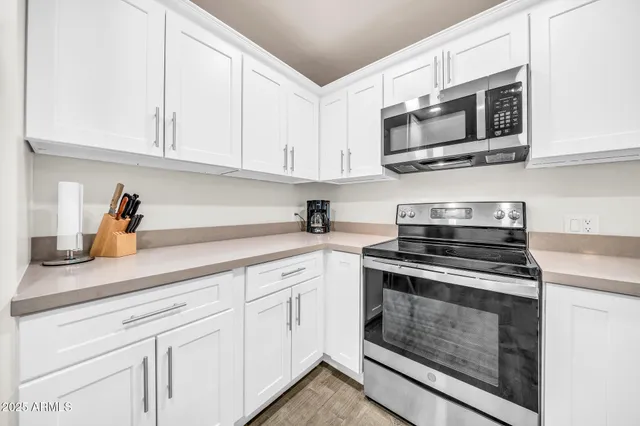 a kitchen with a refrigerator a sink and white cabinets