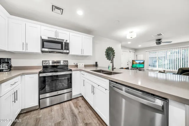 a kitchen with stainless steel appliances granite countertop grey cabinets a stove a sink and dishwasher