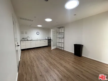 a view of a hallway with wooden floor and a bathroom