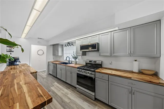 a kitchen with stainless steel appliances granite countertop a sink and cabinets with wooden floor