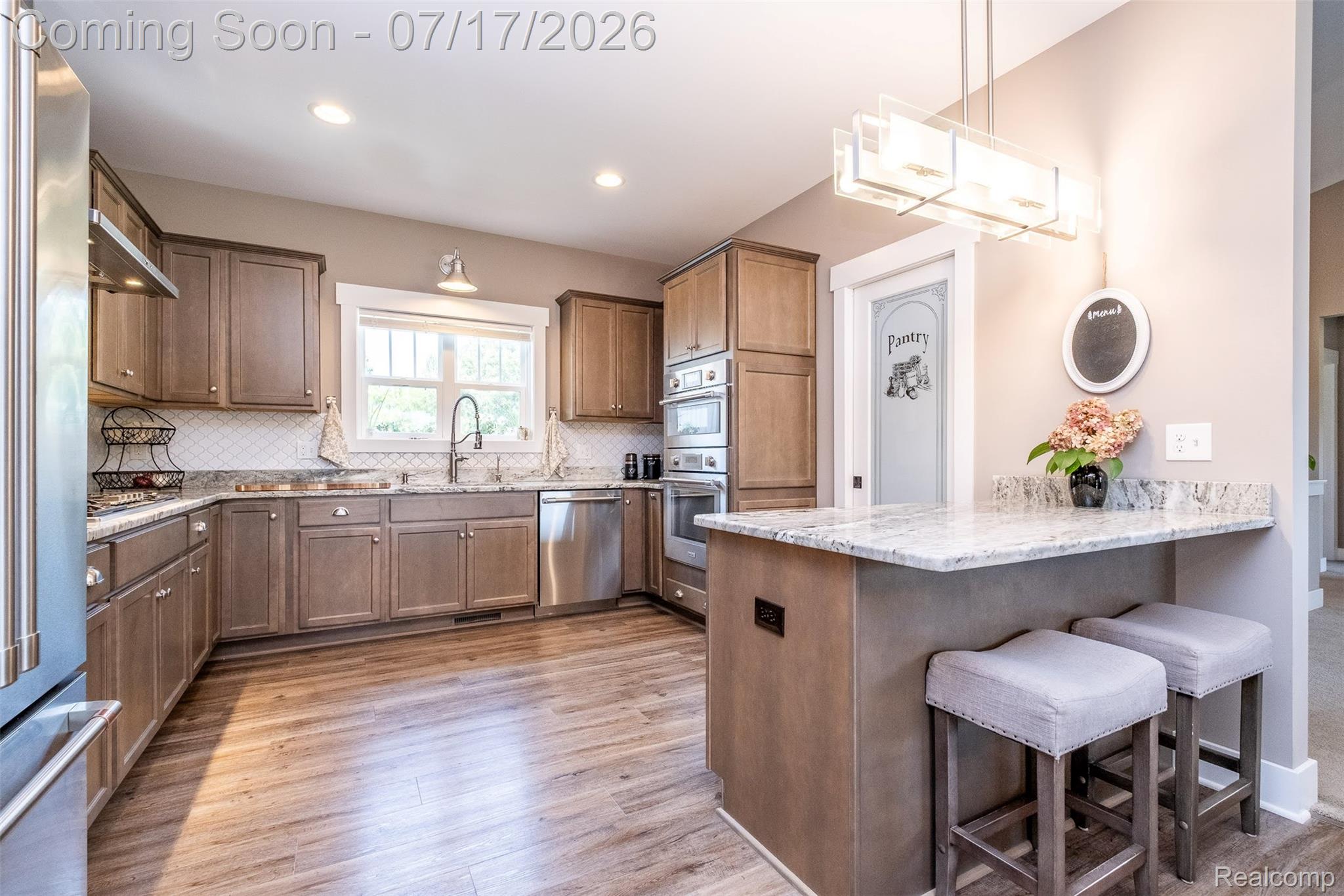 12349 Sugar Maple Drive Fenton, MI 48430 - Photo 14 of 67 Kitchen featuring wood-finish flooring, light wood cabinetry, white subway tile backsplash, and stainless steel appliances