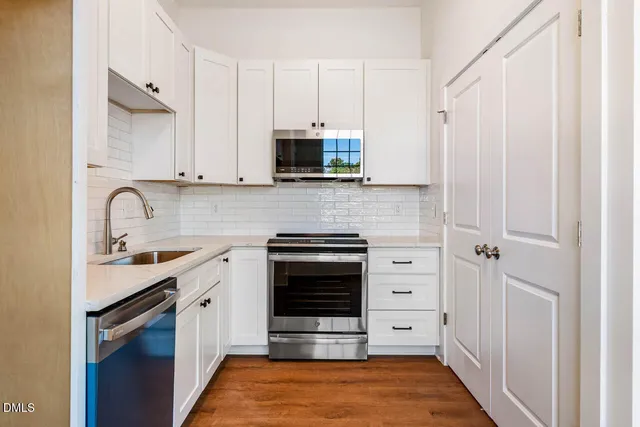 a kitchen with white cabinets and appliances