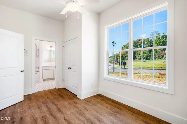 a view of an empty room with wooden floor and a window