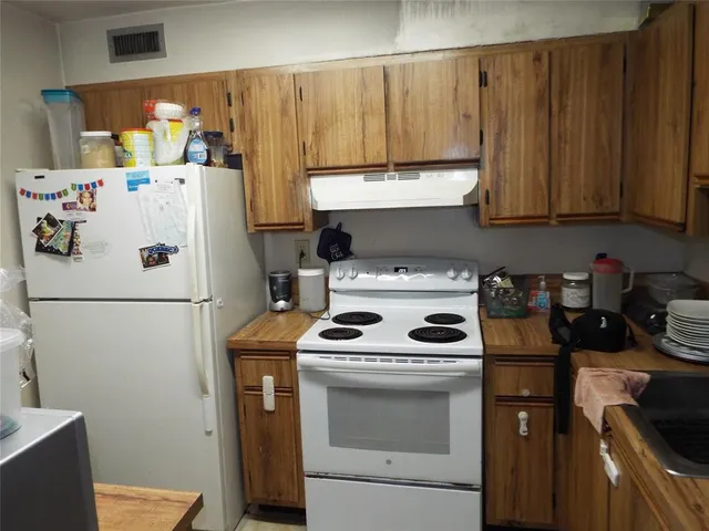 a kitchen with a refrigerator and a stove top oven