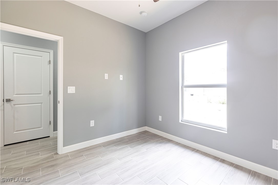 2422 Mae Avenue South Lehigh Acres, FL 33973 - Photo 12 of 28 an empty room with wooden floor and windows