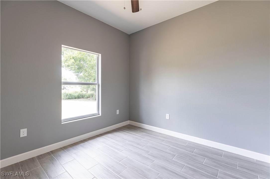 2422 Mae Avenue South Lehigh Acres, FL 33973 - Photo 18 of 28 an empty room with wooden floor and windows