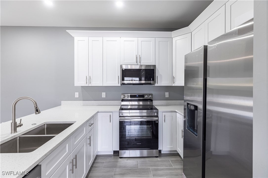 2422 Mae Avenue South Lehigh Acres, FL 33973 - Photo 9 of 28 a kitchen with stainless steel appliances granite countertop a refrigerator sink and stove