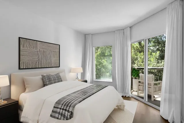 a bedroom with a balcony a bed and a large window