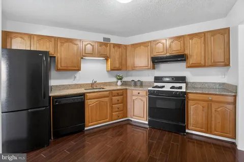 a kitchen with granite countertop a refrigerator stove and sink