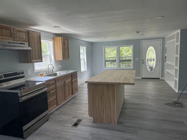 a kitchen with stainless steel appliances granite countertop a stove a sink dishwasher and microwave with wooden floor