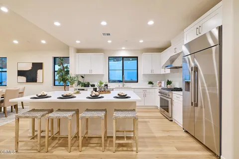 a kitchen with stainless steel appliances kitchen island granite countertop a refrigerator and a stove top oven