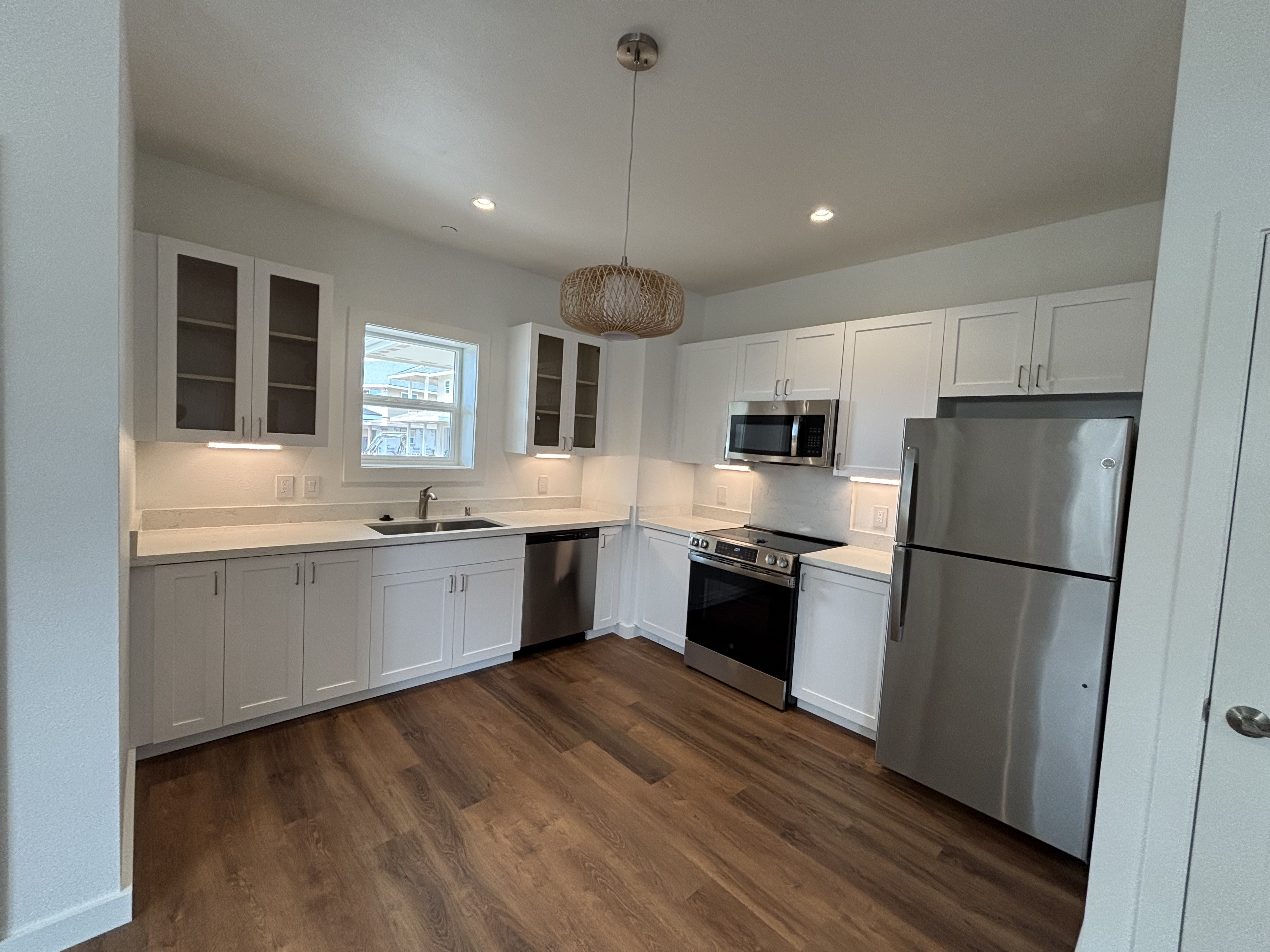 3451 Waikomo Road, Unit D102 Koloa, HI 96756 - Photo 5 of 15 a large kitchen with a refrigerator a sink dishwasher a oven with white cabinets and wooden floor