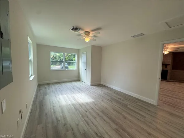 a view of empty room with wooden floor and fan