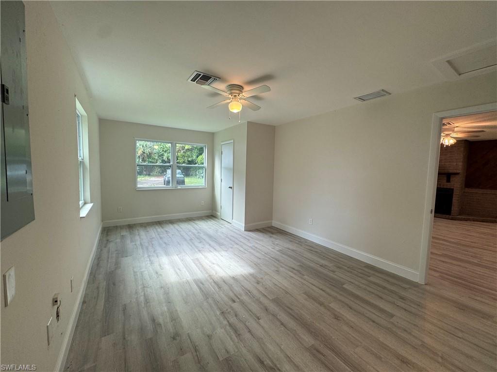 221 18th Avenue Northwest Naples, FL 34120 - Photo 10 of 22 an empty room with wooden floor chandelier fan and windows