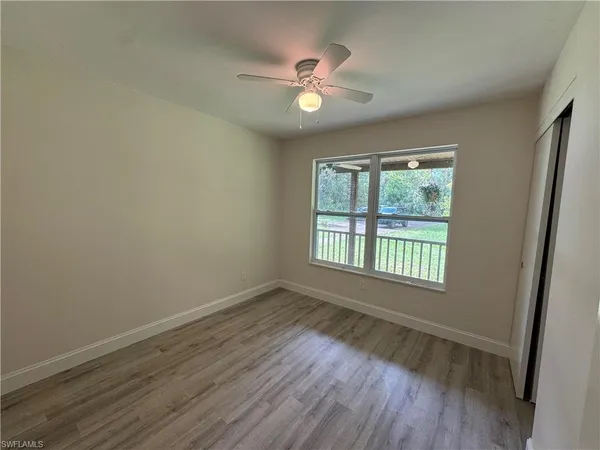 an empty room with windows and ceiling fan