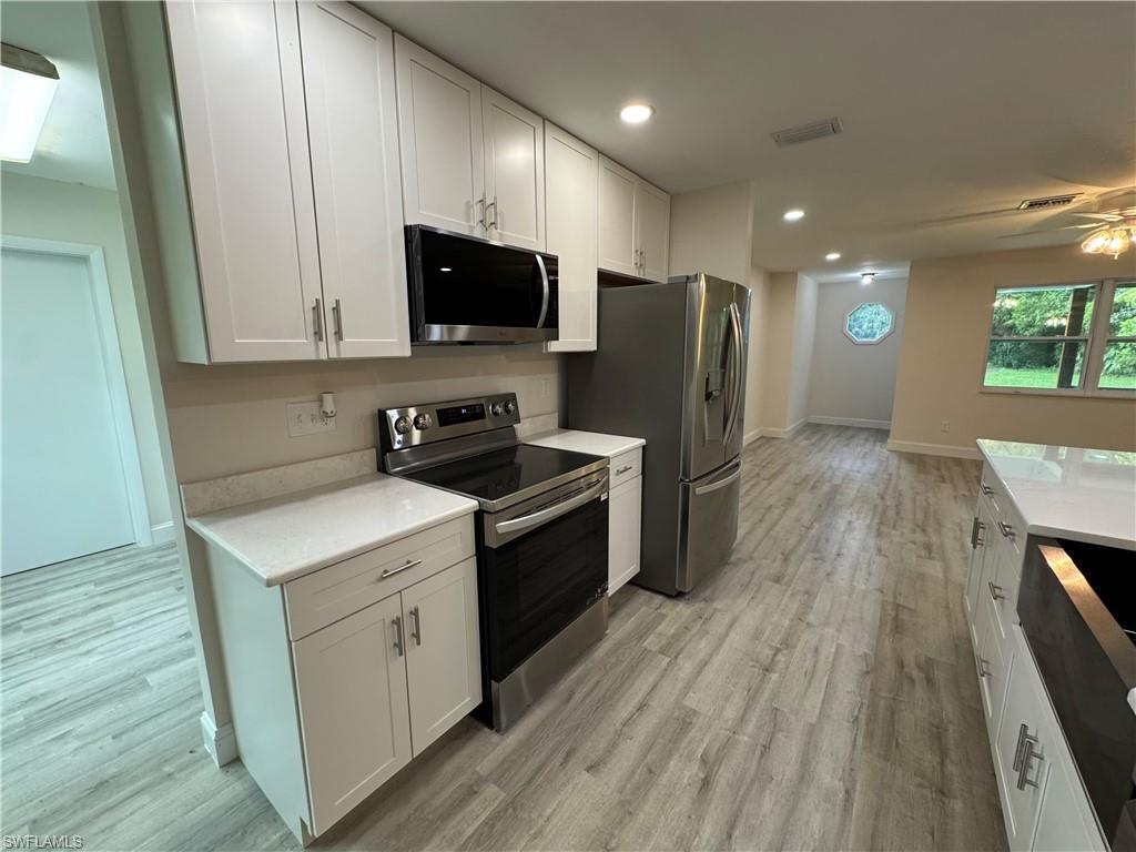 221 18th Avenue Northwest Naples, FL 34120 - Photo 3 of 22 a kitchen with a microwave a sink dishwasher a refrigerator and a stove with wooden floor