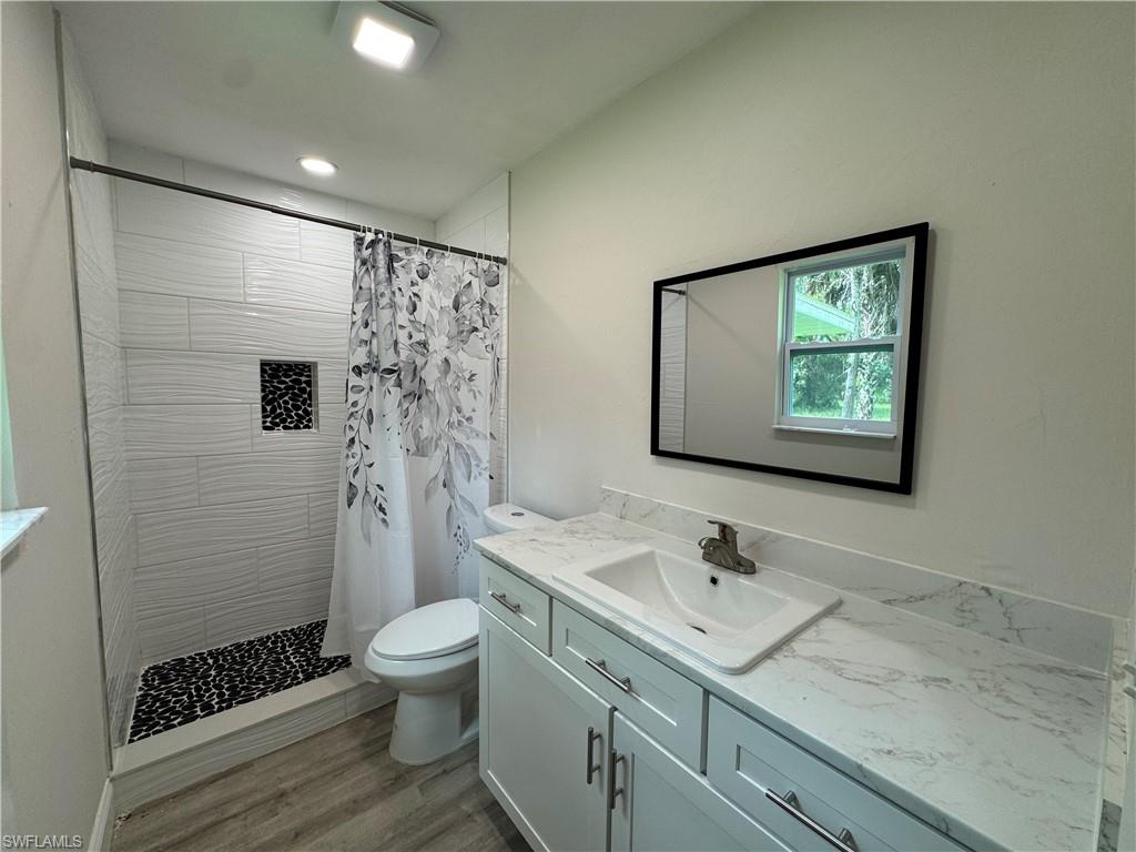 221 18th Avenue Northwest Naples, FL 34120 - Photo 8 of 22 a bathroom with a granite countertop sink a toilet and shower