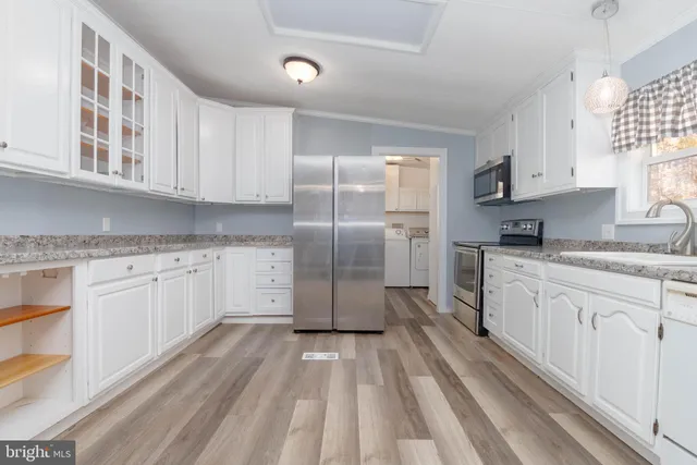 a kitchen with granite countertop a refrigerator sink and cabinets