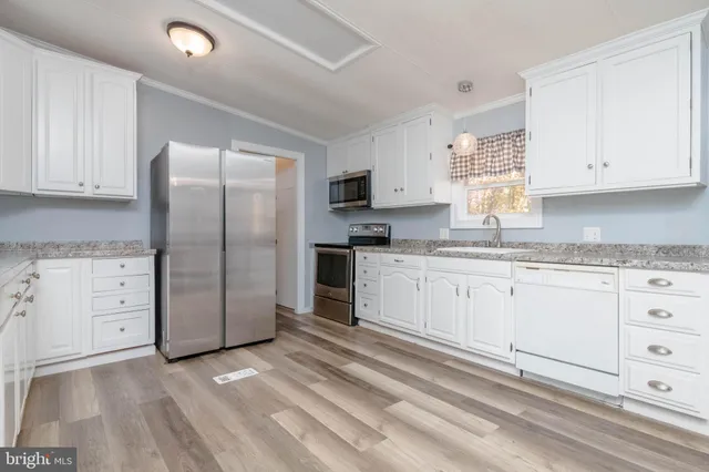 a kitchen with granite countertop white cabinets and stainless steel appliances