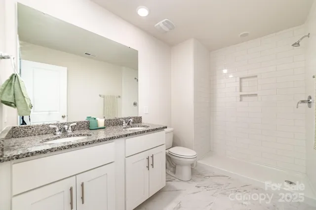 a bathroom with a granite countertop sink a toilet and a mirror