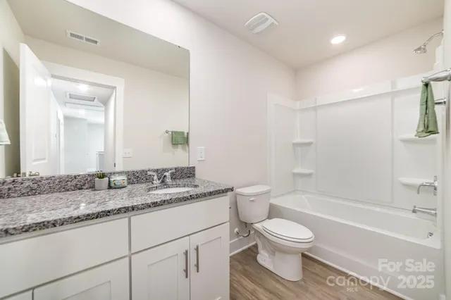 a bathroom with a granite countertop sink toilet a large mirror a bathtub and shower