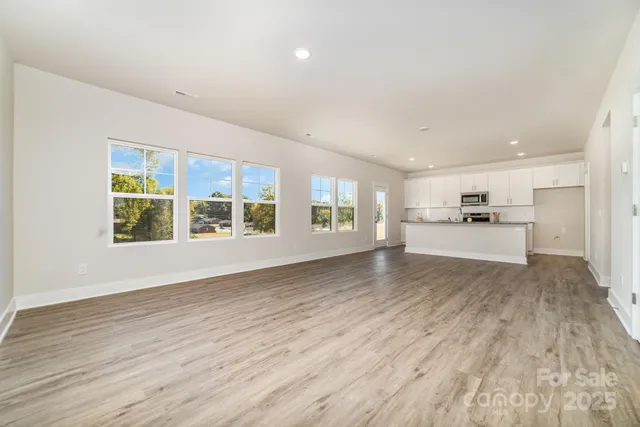 a view of an empty room with kitchen and a window