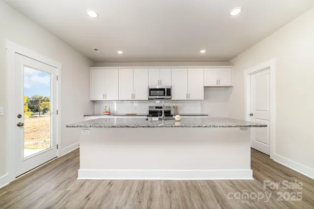 a kitchen with stainless steel appliances granite countertop a stove a sink and a granite counter tops with wooden floors