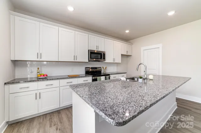 a kitchen with granite countertop a sink a stove and cabinets