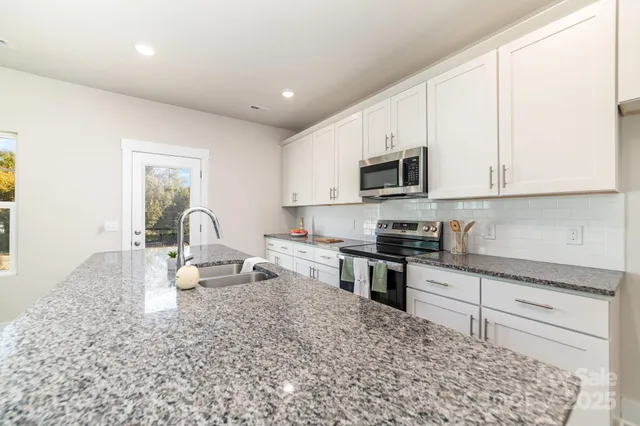 a kitchen with stainless steel appliances granite countertop a stove a sink and a microwave