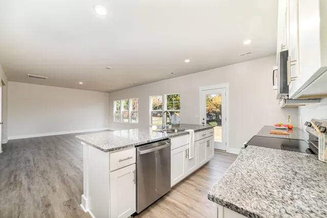 a kitchen with stainless steel appliances granite countertop a sink stove and cabinets