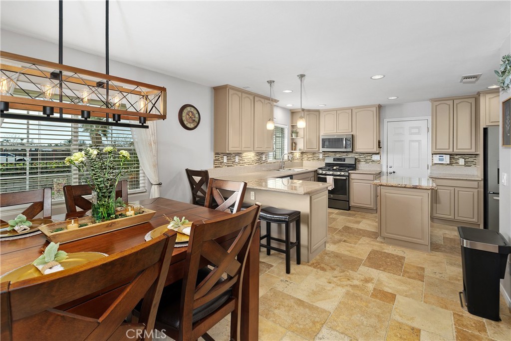 34990 County Line Road Yucaipa, CA 92399 - Photo 15 of 51 a kitchen with stainless steel appliances granite countertop a stove top oven a sink a dining table and chairs with the view of living room