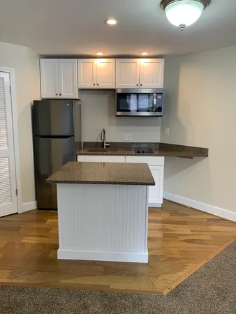 a kitchen with kitchen island granite countertop a sink a stove a refrigerator cabinets and a counter top space