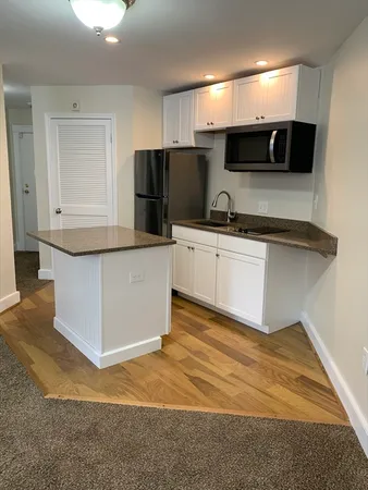 a kitchen with stainless steel appliances a refrigerator a stove a sink and white cabinets