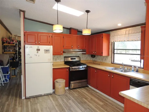 a kitchen with granite countertop a refrigerator stove top oven and sink
