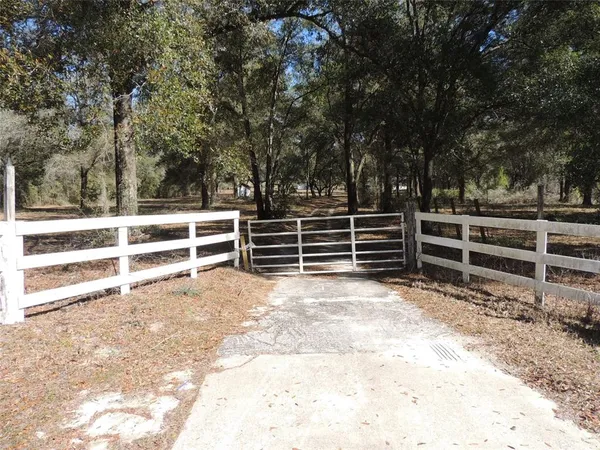 a view of an empty room with wooden fence and large trees