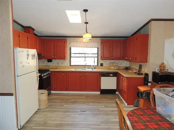 a kitchen with stainless steel appliances granite countertop a stove a sink dishwasher and wooden cabinets with wooden floor