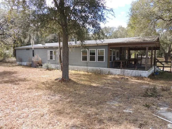 a front view of a house with a yard covered with trees